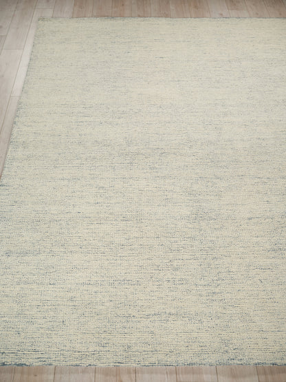 Cream textured area rug with subtle blue-gray linear pattern on light wood floor.