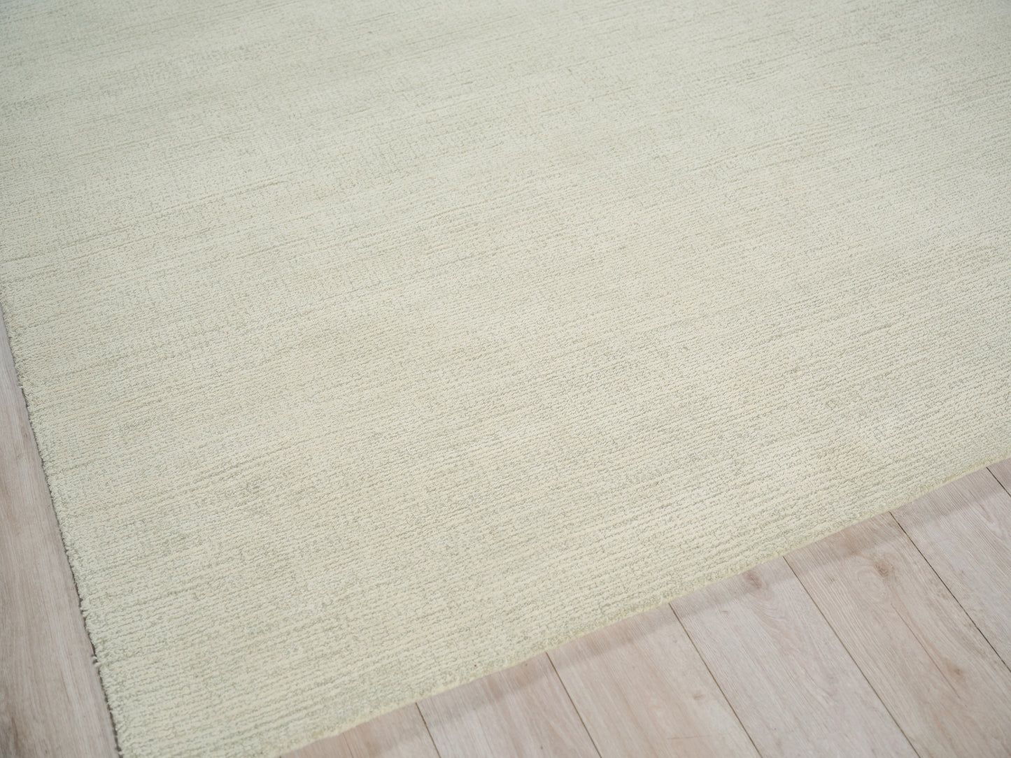 Sage-green textured hand-tufted rug on light wood floor, rectangular and cozy underfoot.