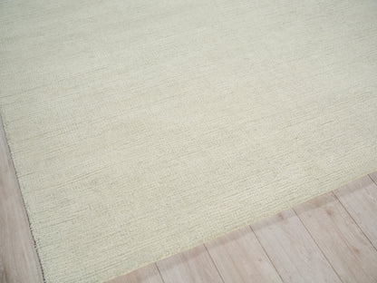 Sage-green textured hand-tufted rug on light wood floor, rectangular and cozy underfoot.