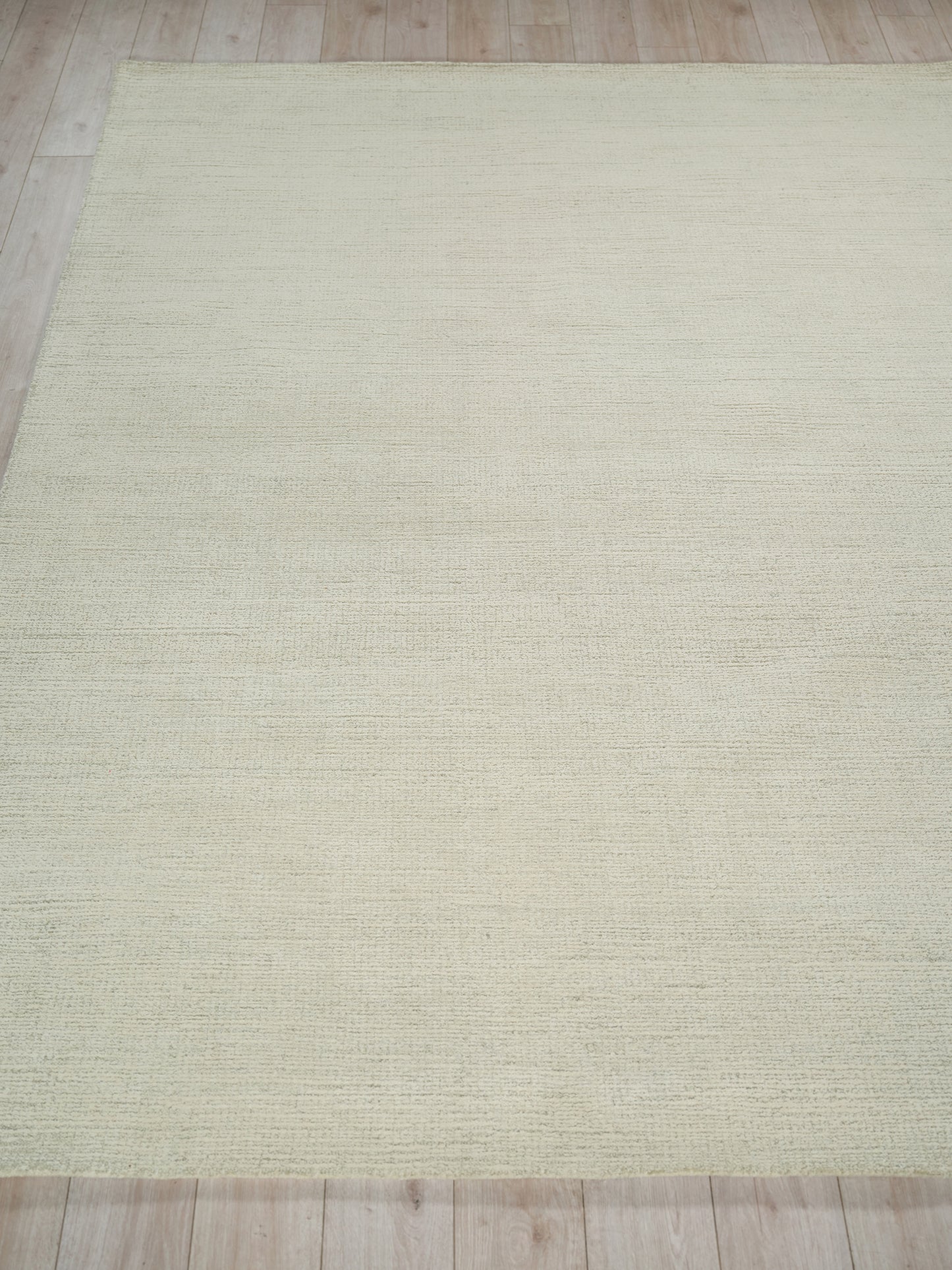 Cream textured indoor hand-tufted rug with subtle horizontal weave on light wood floor.