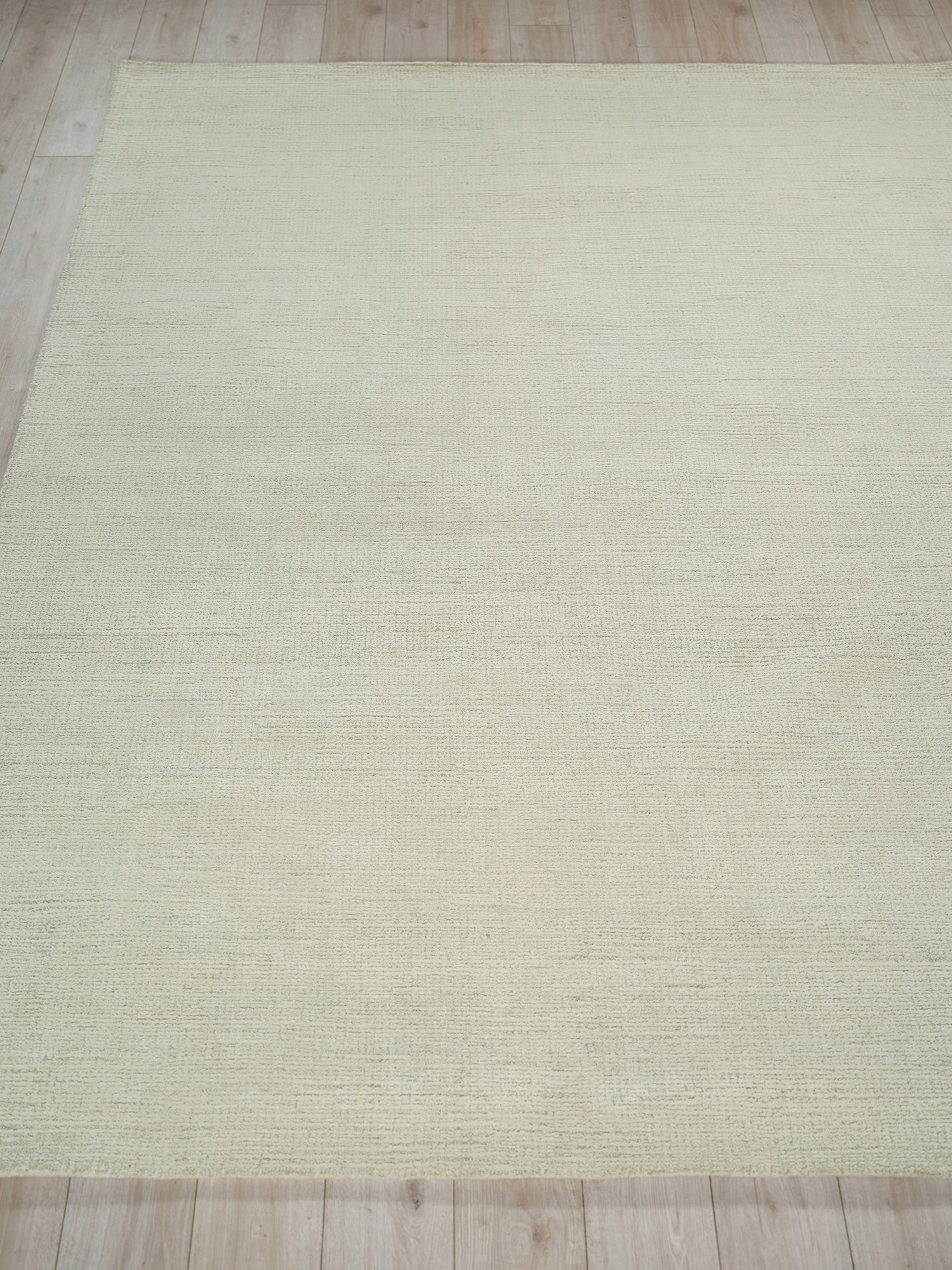 Cream textured indoor hand-tufted rug with subtle horizontal weave on light wood floor.