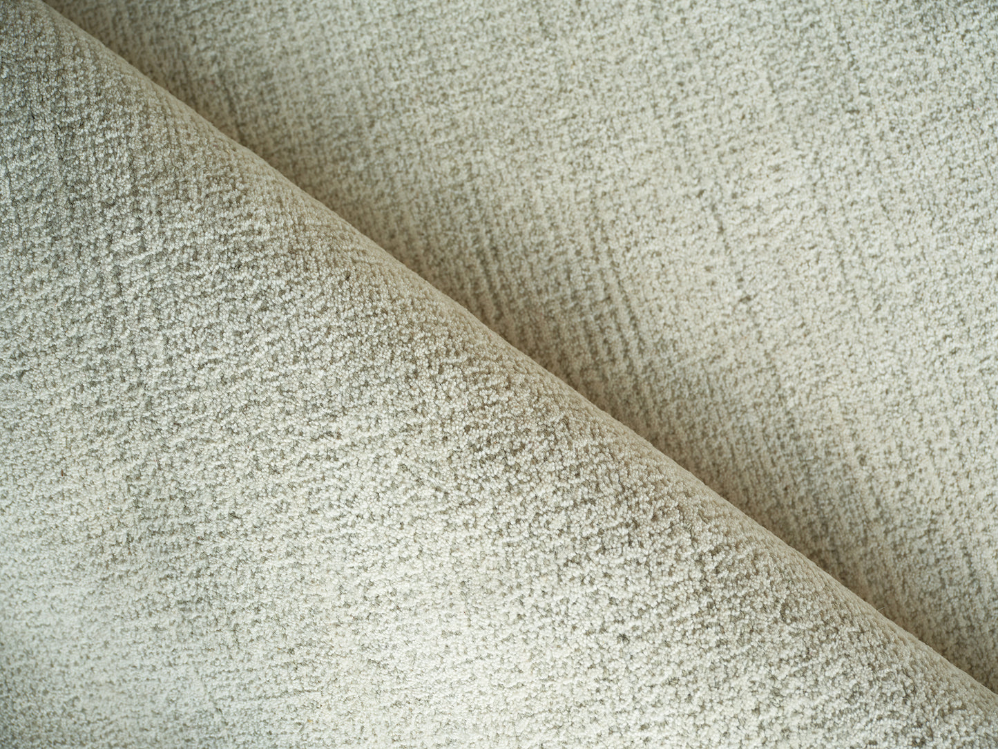 Beige boucle rug close-up showing soft textured weave and diagonal fold