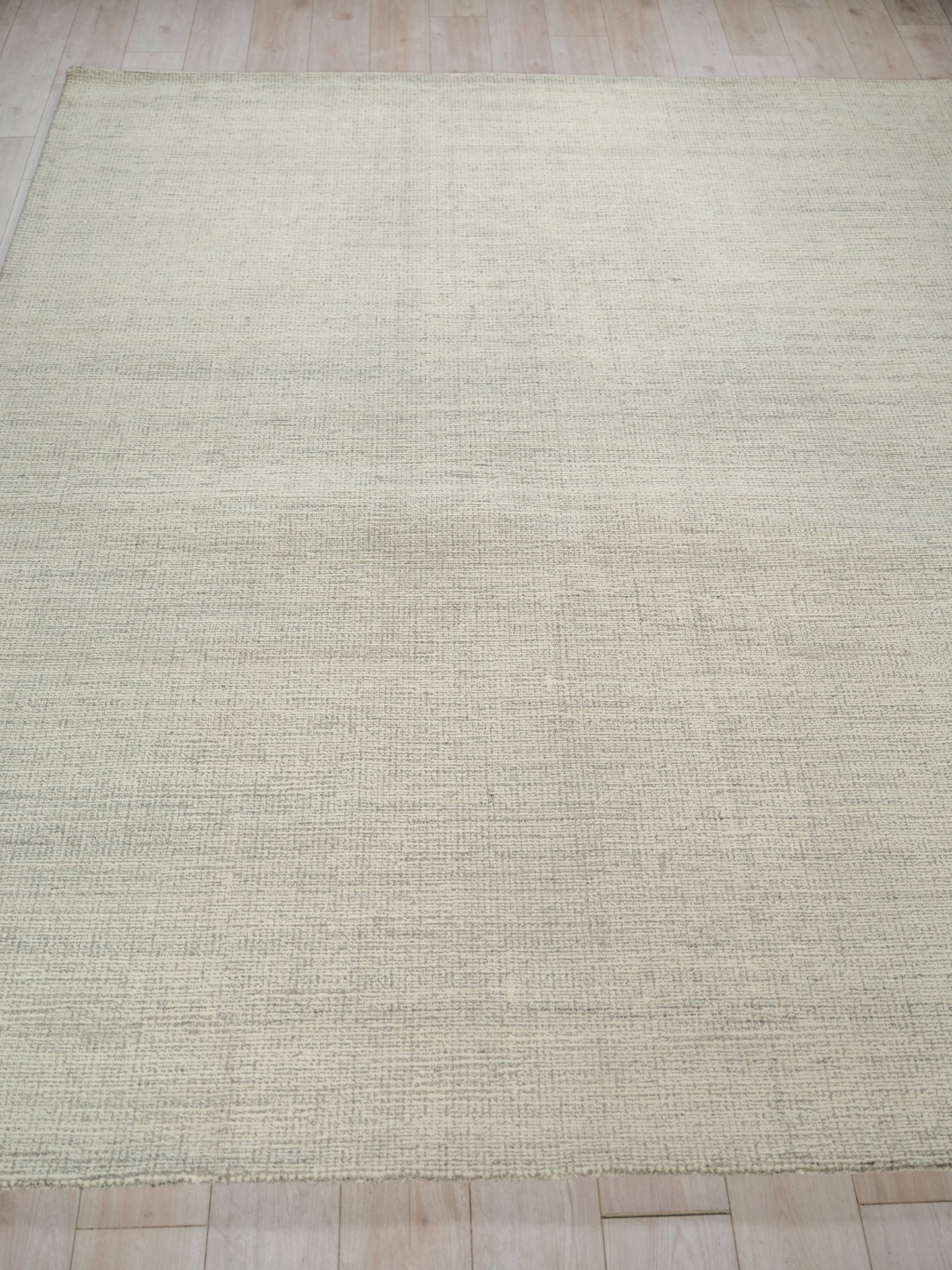 Rectangular cream-beige hand-tufted rug with subtle texture on light wood floor.