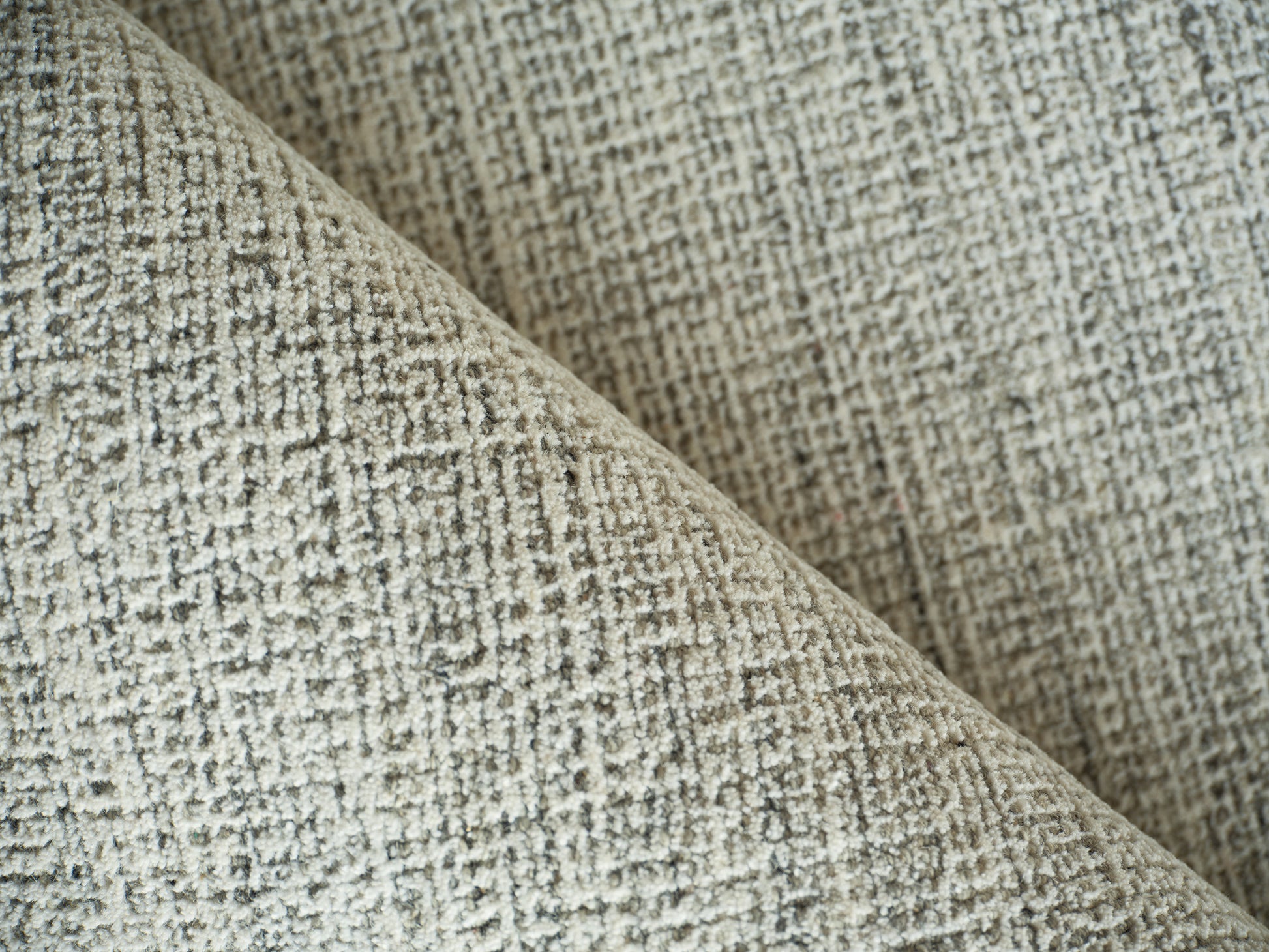 Beige & gray tweed-style woven rug close-up with a diagonal fold.
