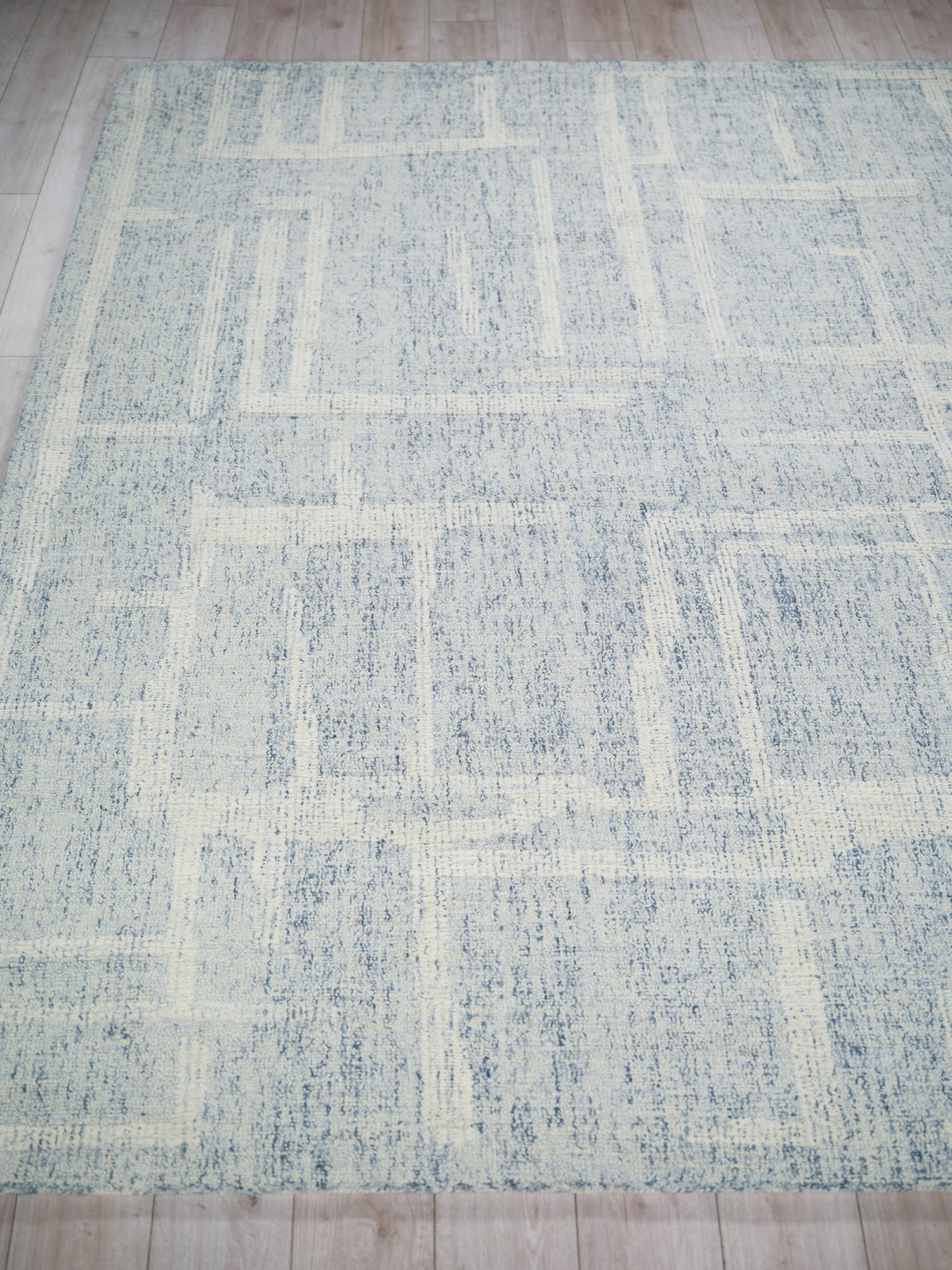 Rectangular blue-gray and ivory abstract patchwork rug, hand-tufted, low-pile for modern living spaces.