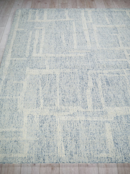 Rectangular blue-gray and ivory abstract patchwork rug, hand-tufted, low-pile for modern living spaces.