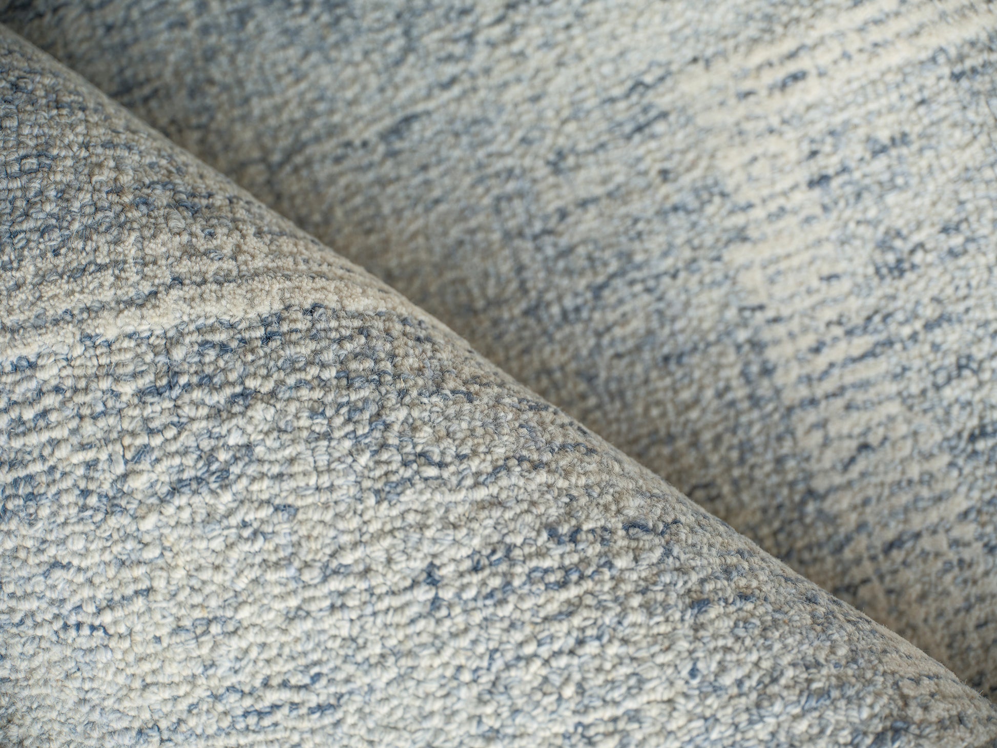Close-up of a light blue-gray boucle rug with speckled heather texture and soft loop pile.