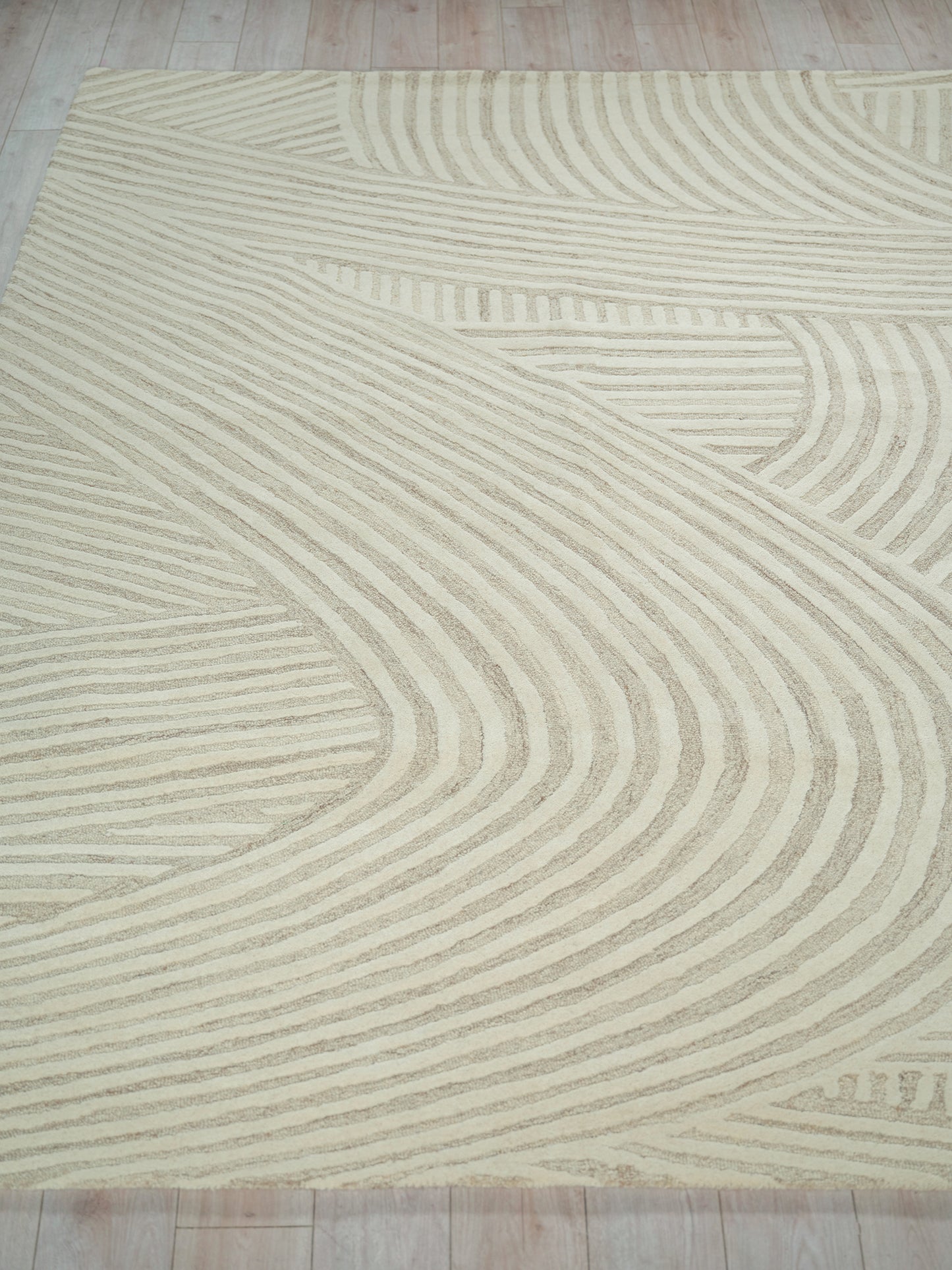 Beige area rug with cream curved line pattern; soft pile and modern geometric design for living areas.