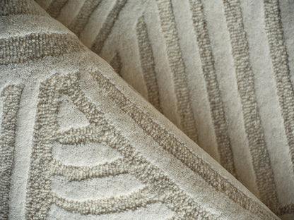 Beige hand-tufted rug with embossed leaf motif & striped border, 4' x 6'.