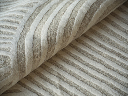 Beige and taupe striped plush rug with textured terry loops, rolled edge.