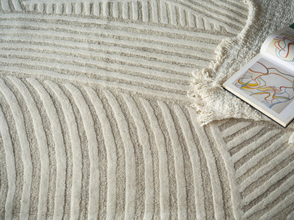 Cream shag rug with raised curved stripe pattern and fringe, beside an open art book with colorful abstract lines.