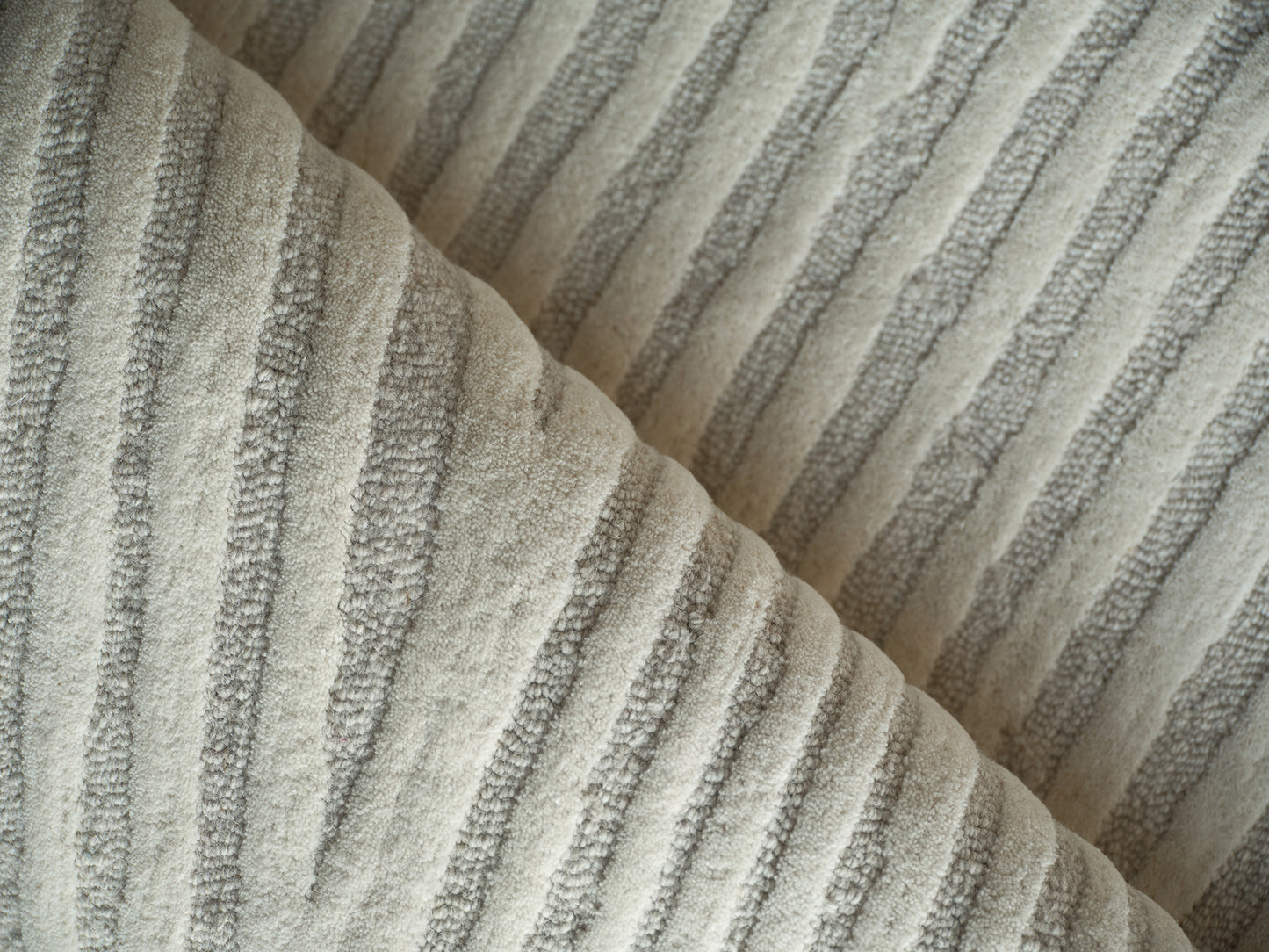 Beige striped hand-tufted rug with ribbed texture, folded to show stripes, 4' x 6'.