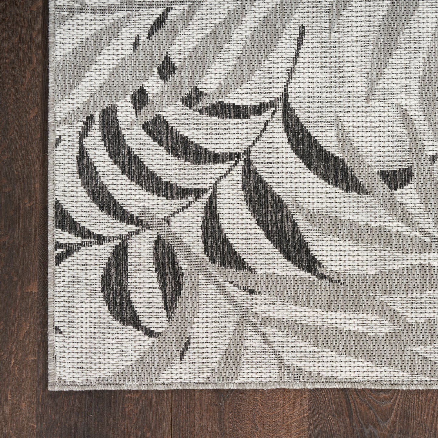 Rectangular gray and ivory woven area rug with black botanical leaf pattern; textured jacquard weave.