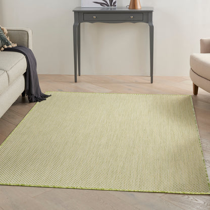 Rectangular light olive-green woven rug in a cozy living room with a gray console table, beige sofa and armchair.