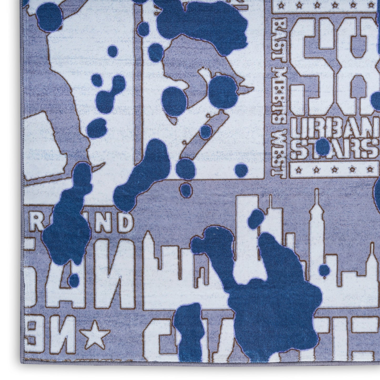 Lavender-blue throw blanket with white city skyline silhouettes and navy paint splatters in a bold urban print.