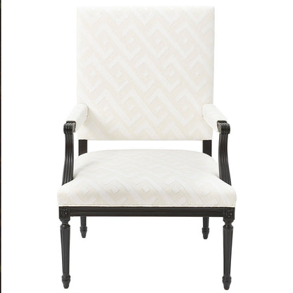 Cream geometric patterned upholstered armchair with tall back, dark carved wood frame and tapered legs.