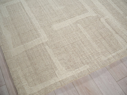 Beige rectangular hand-tufted rug with subtle cream and tan geometric blocks on light wood floor.