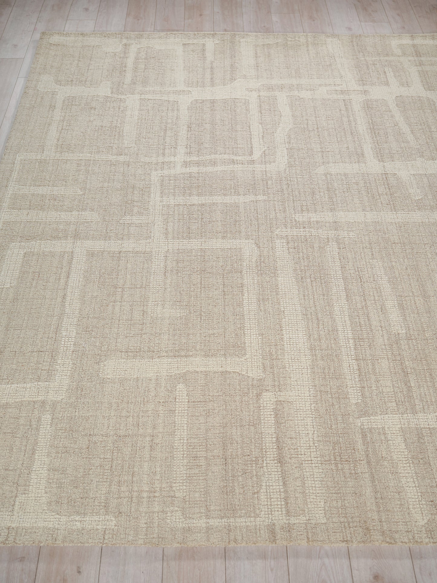 Beige rectangular area rug with a subtle geometric block pattern in lighter and darker beige, woven texture.