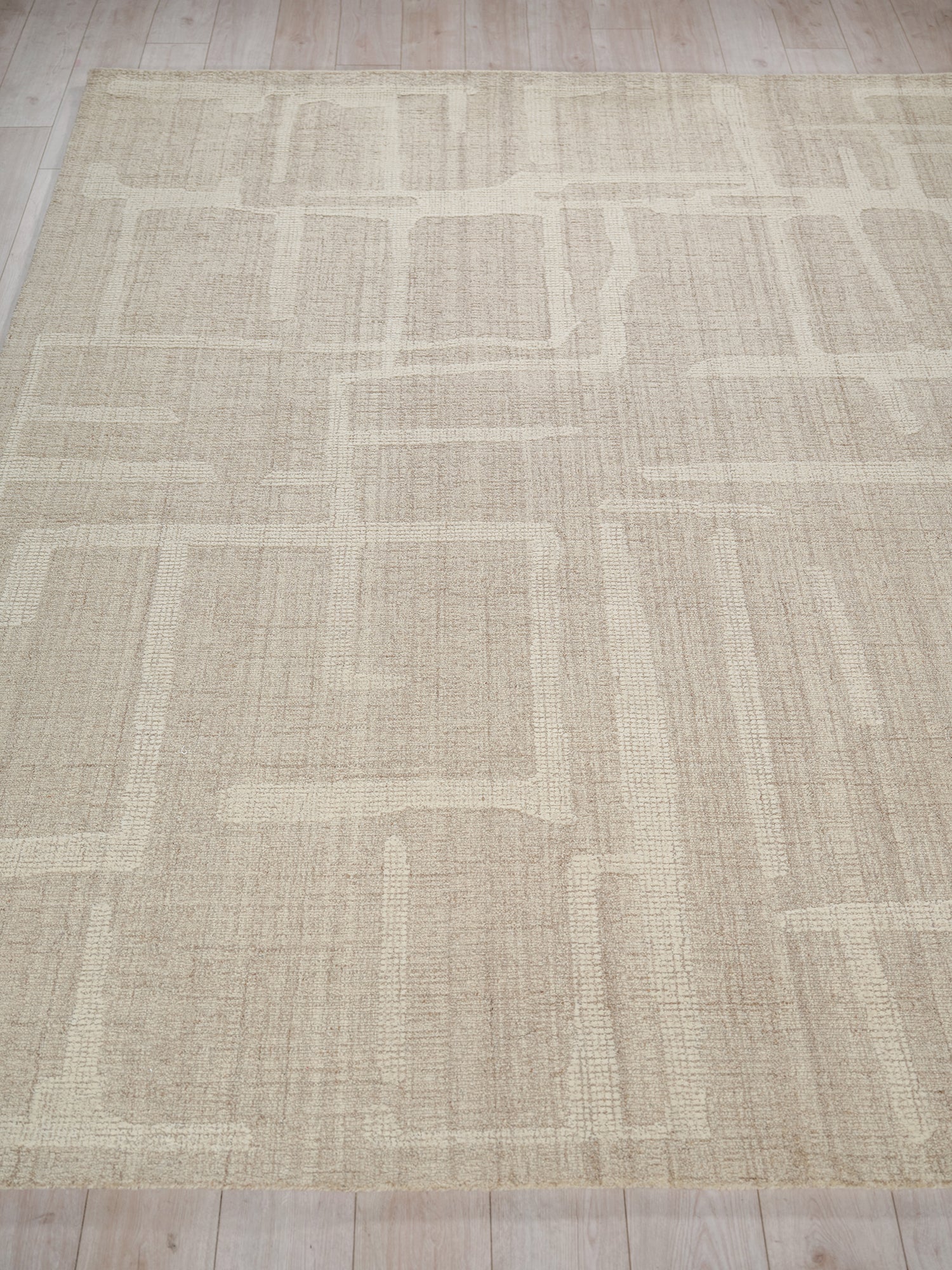 Beige rectangular area rug with a subtle geometric block pattern in lighter and darker beige, woven texture.