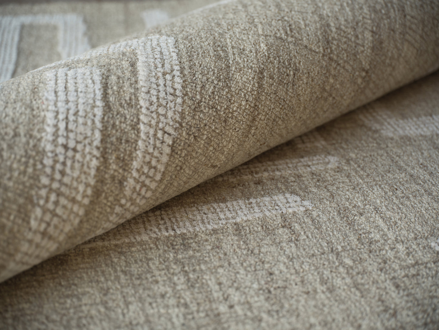 Beige hand-tufted area rug with subtle geometric patterns, rolled edge and soft texture for neutral decor.