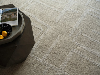 Beige textured rug on the floor with a dark coffee table; a light gray tray on the table holds black grapes, yellow lemons, and an open magazine.