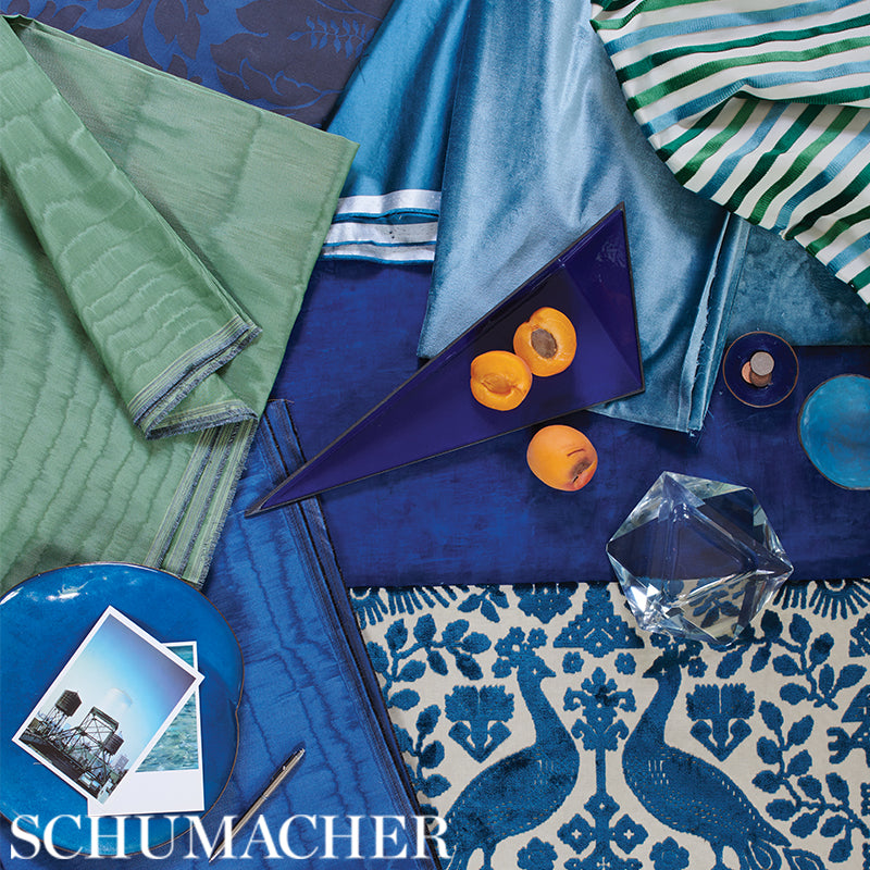 Blue, teal, and green silky striped fabrics (satin and silk) with a purple triangular decor piece and a glass crystal; peacock-patterned fabric.