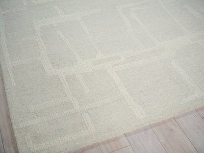 Beige textured area rug with a subtle geometric square pattern on a light wood floor.