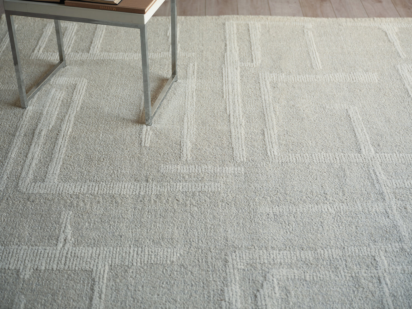 Light gray textured area rug with a geometric rectangular border pattern.