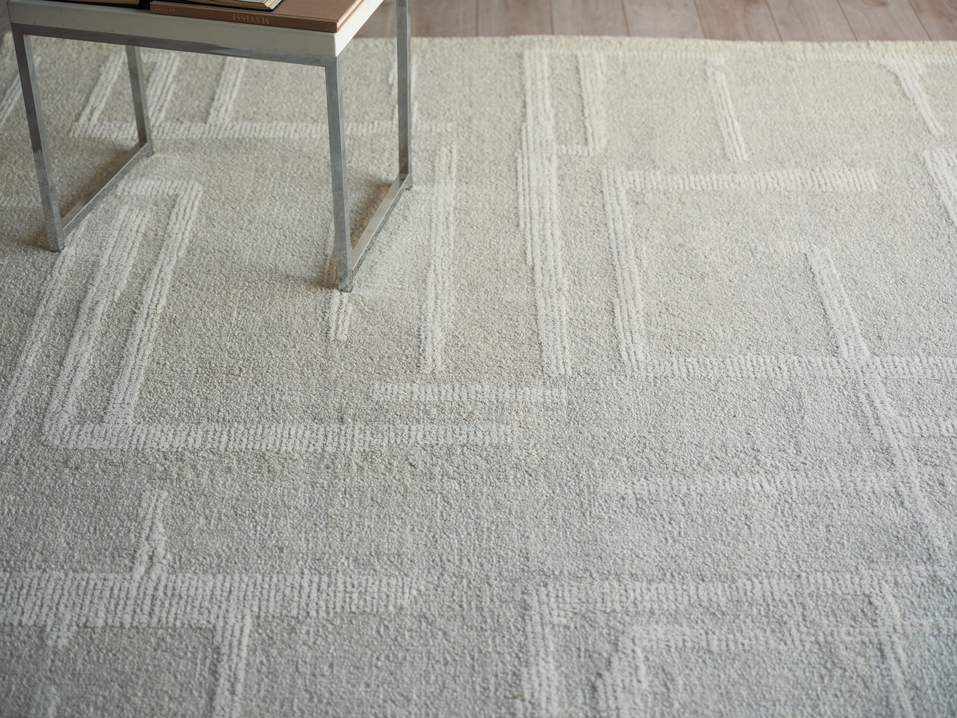 Light gray textured area rug with a geometric rectangular border pattern.
