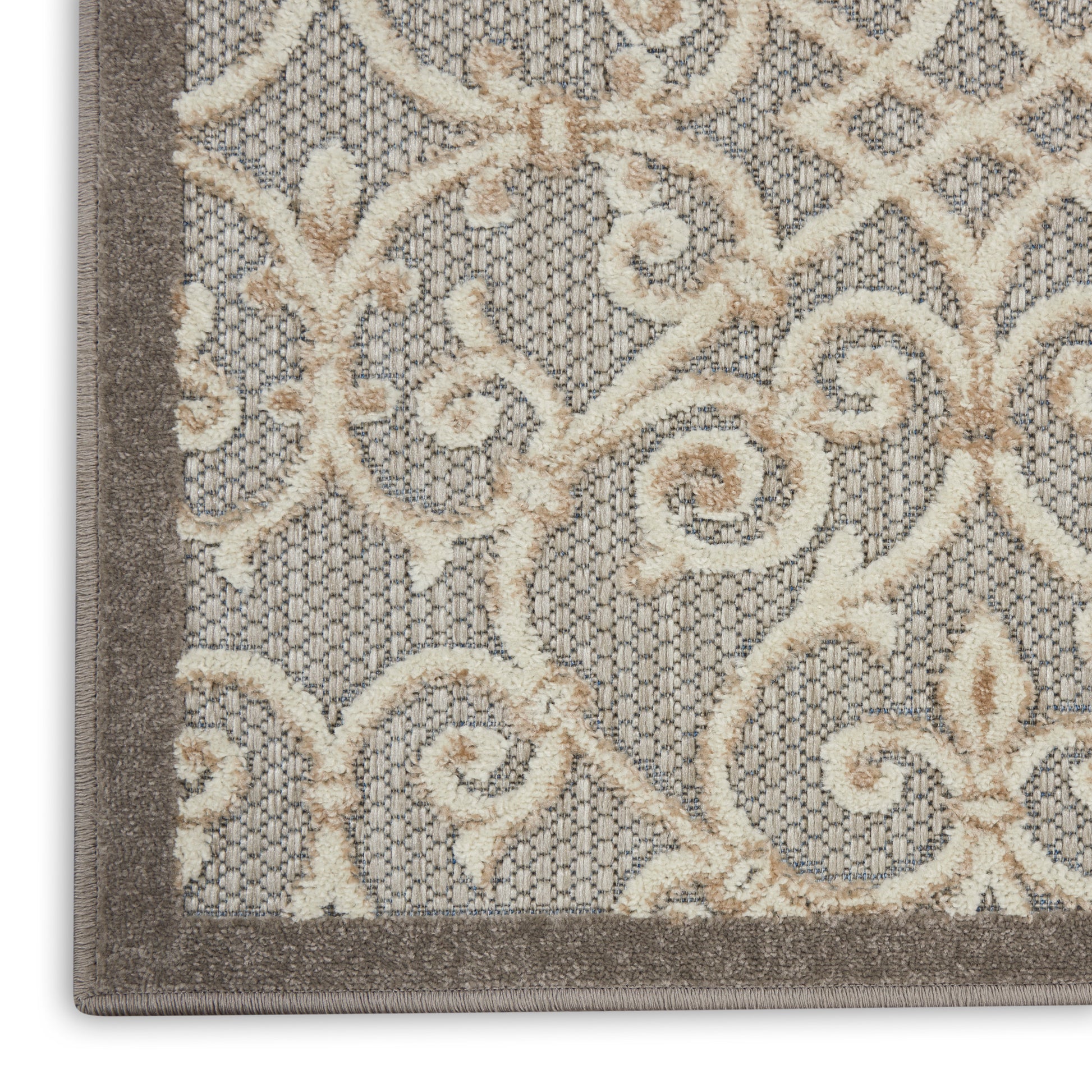 Close-up of gray area rug with cream-beige ornate scrolling pattern and dark border; tufted texture.