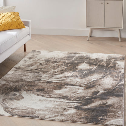Rectangular plush area rug with abstract taupe, brown and cream swirls in a modern living room on light wood floor.