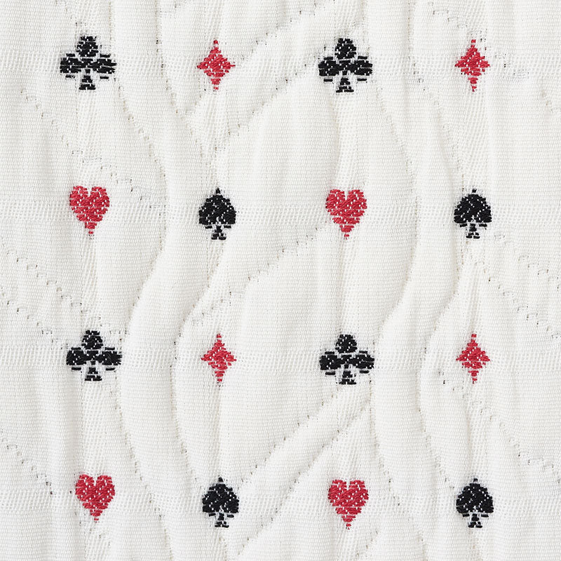 White quilted fabric with subtle wavy stitching and a repeating pattern of red hearts, red diamonds, and black clubs.