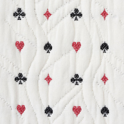 White quilted fabric with subtle wavy stitching and a repeating pattern of red hearts, red diamonds, and black clubs.