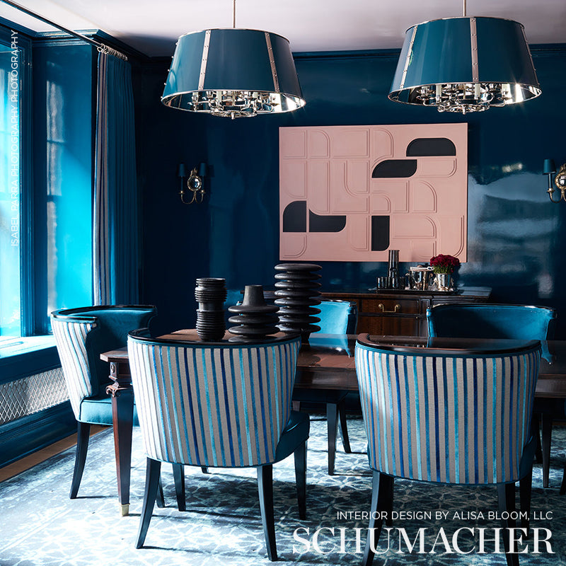 Teal-striped upholstered dining chairs around a dark wood table under teal pendant lamps; pink abstract wall art.