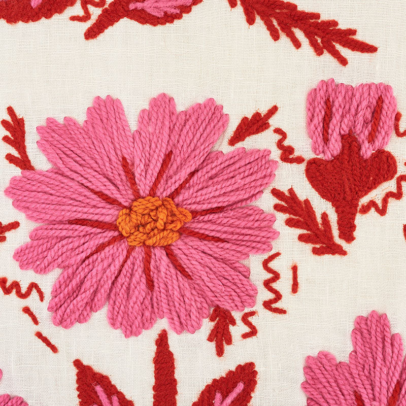 Large pink yarn-embroidered flower with orange center on cream fabric, red leafy accents.