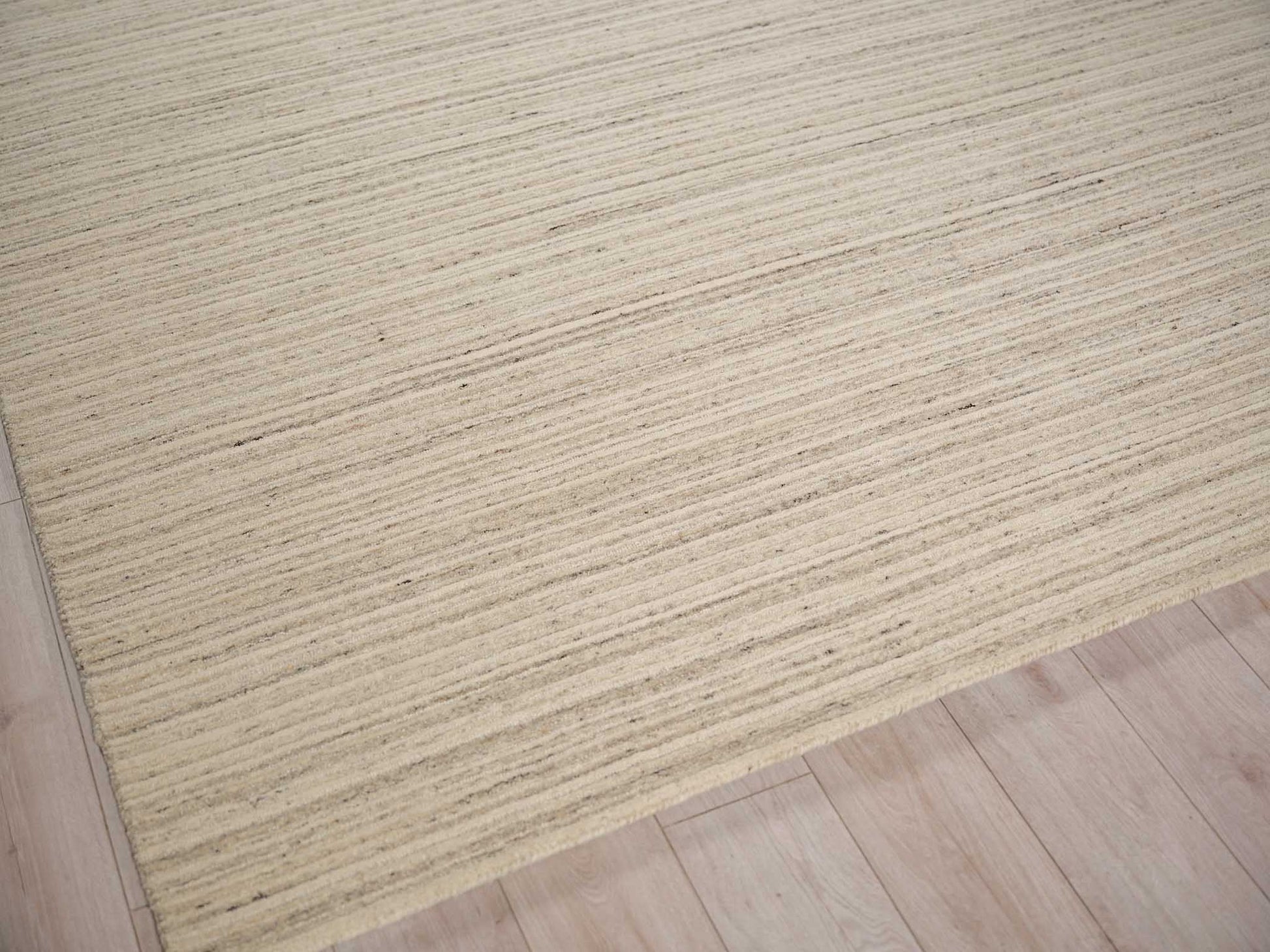 Beige striped rug with subtle tan lines on light wood floor.
