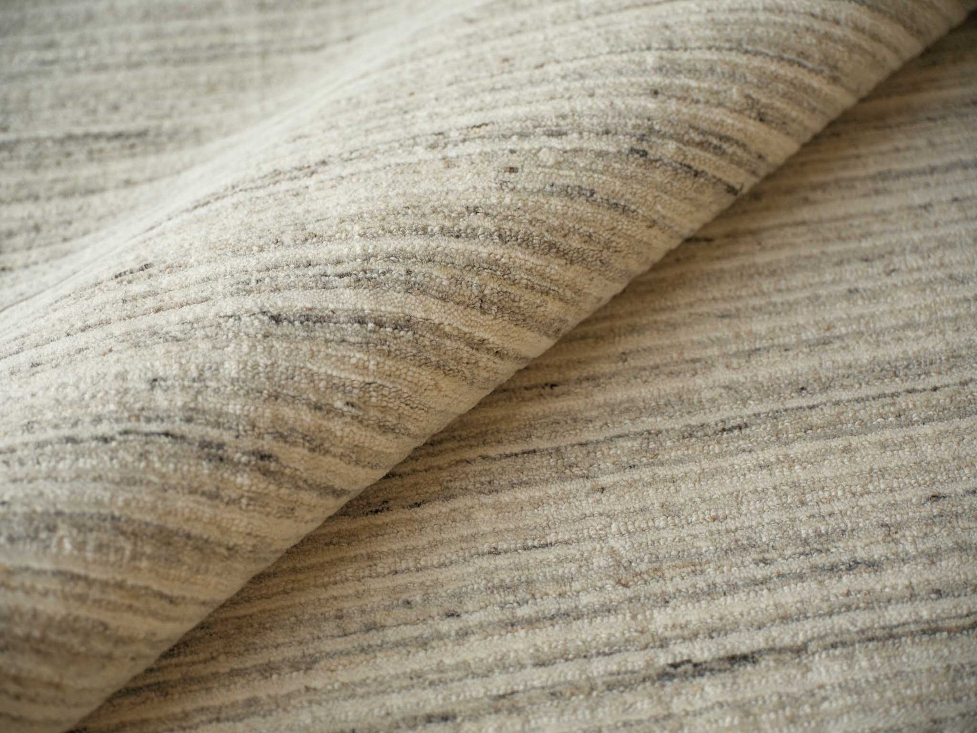 Beige and cream striped woven rug fabric with a soft texture, shown rolled.
