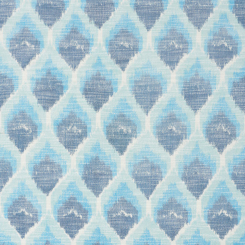 Blue ikat-inspired geometric textile with repeating teardrop/diamond shapes in light to dark blues.