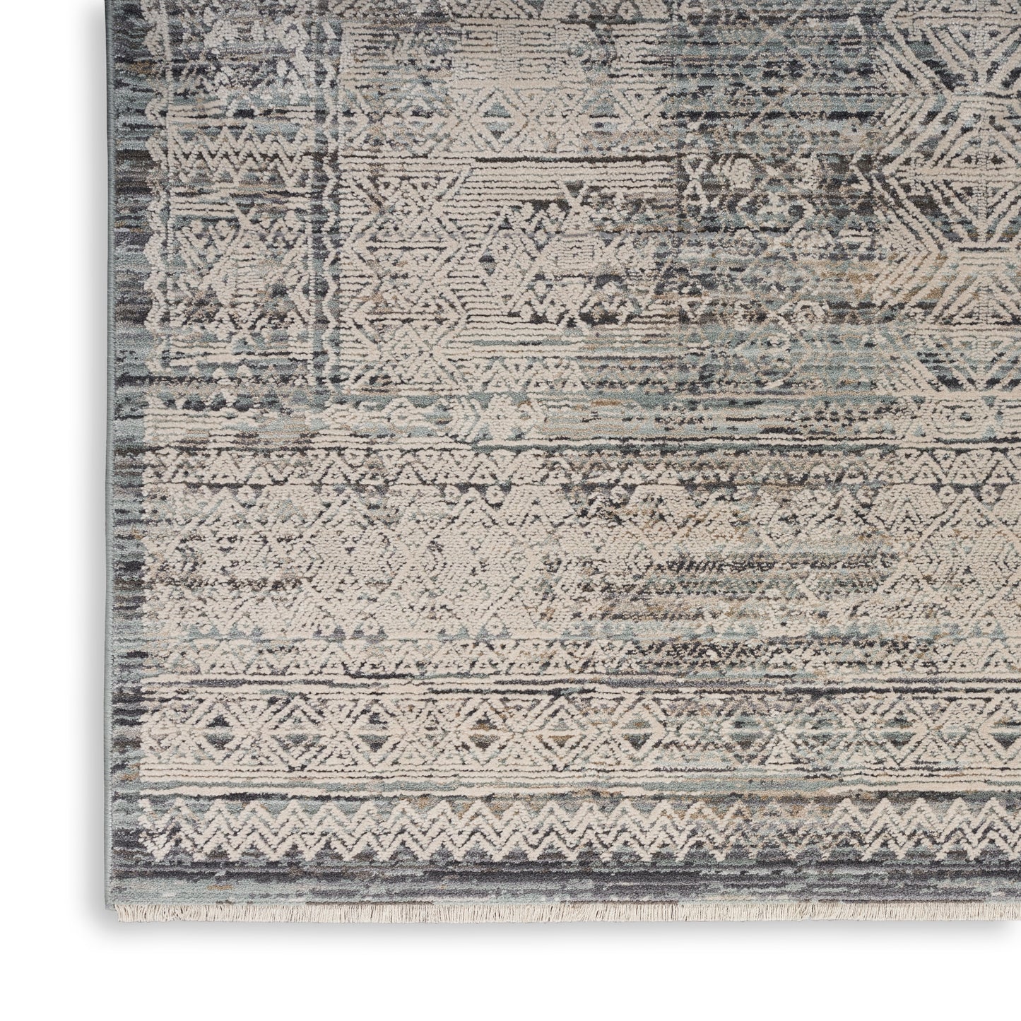 Rectangular woven rug with distressed blue-gray tones and ivory geometric motifs, fringe edge.