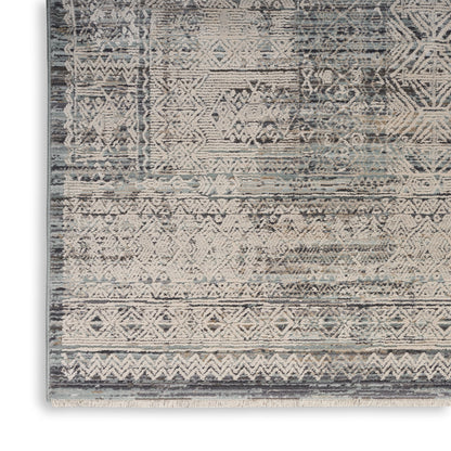 Rectangular woven rug with distressed blue-gray tones and ivory geometric motifs, fringe edge.