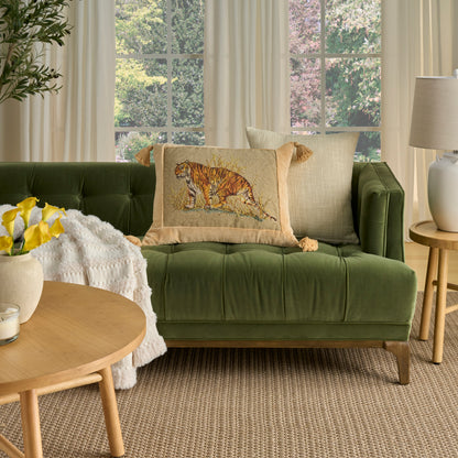 Green velvet sofa with tiger-print pillow, beige cushions, round wood coffee table, yellow flowers, white throw.