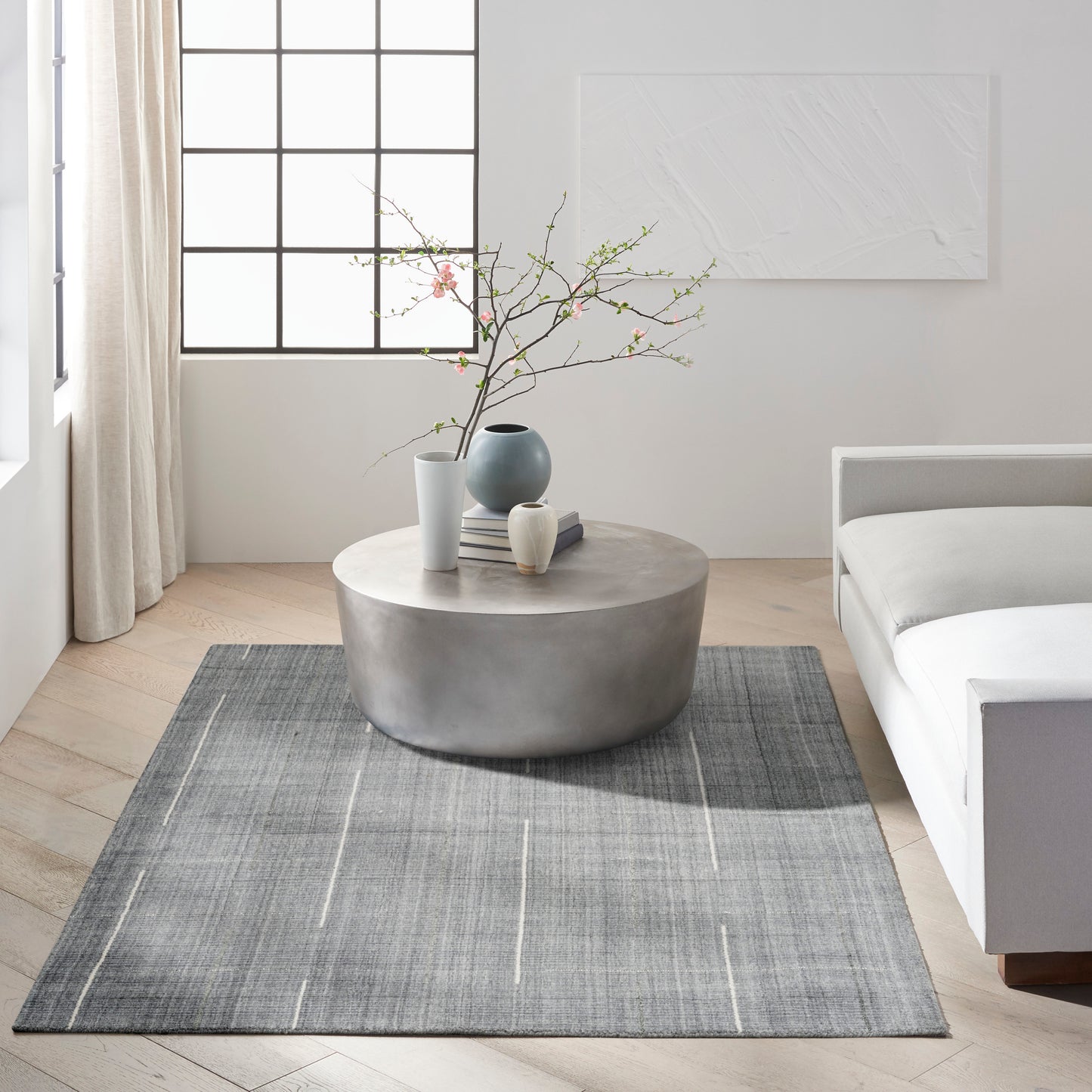 Gray rug in a modern living room with pink blossom vases on it, size 5' x 7'.