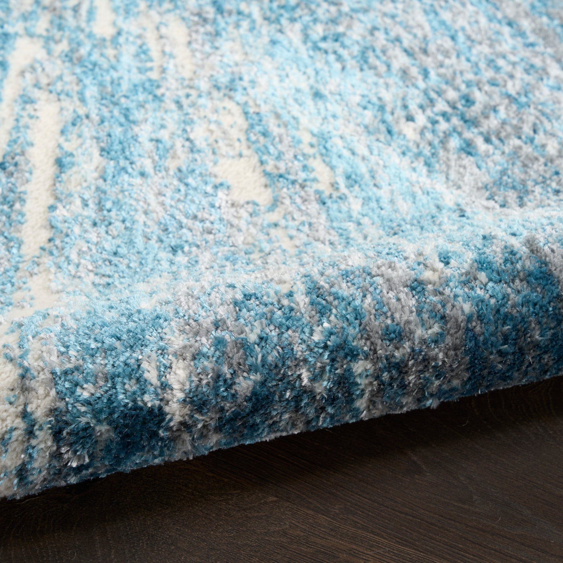 Blue abstract shag rug with light to dark blue tones and soft plush texture, ideal modern living room floor decor.