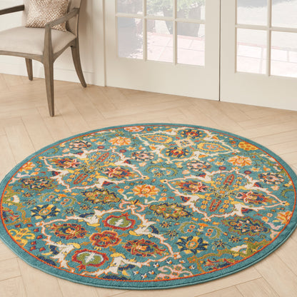 Round turquoise rug with intricate multicolor floral pattern; beige chair and glass doors in a sunlit wood floor room.