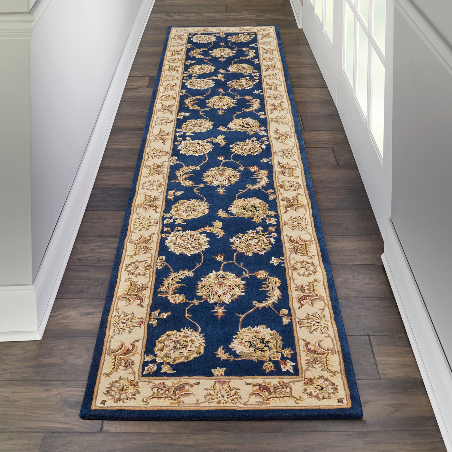 Long navy blue oriental runner rug with a cream floral border and gold accents in a narrow hallway.