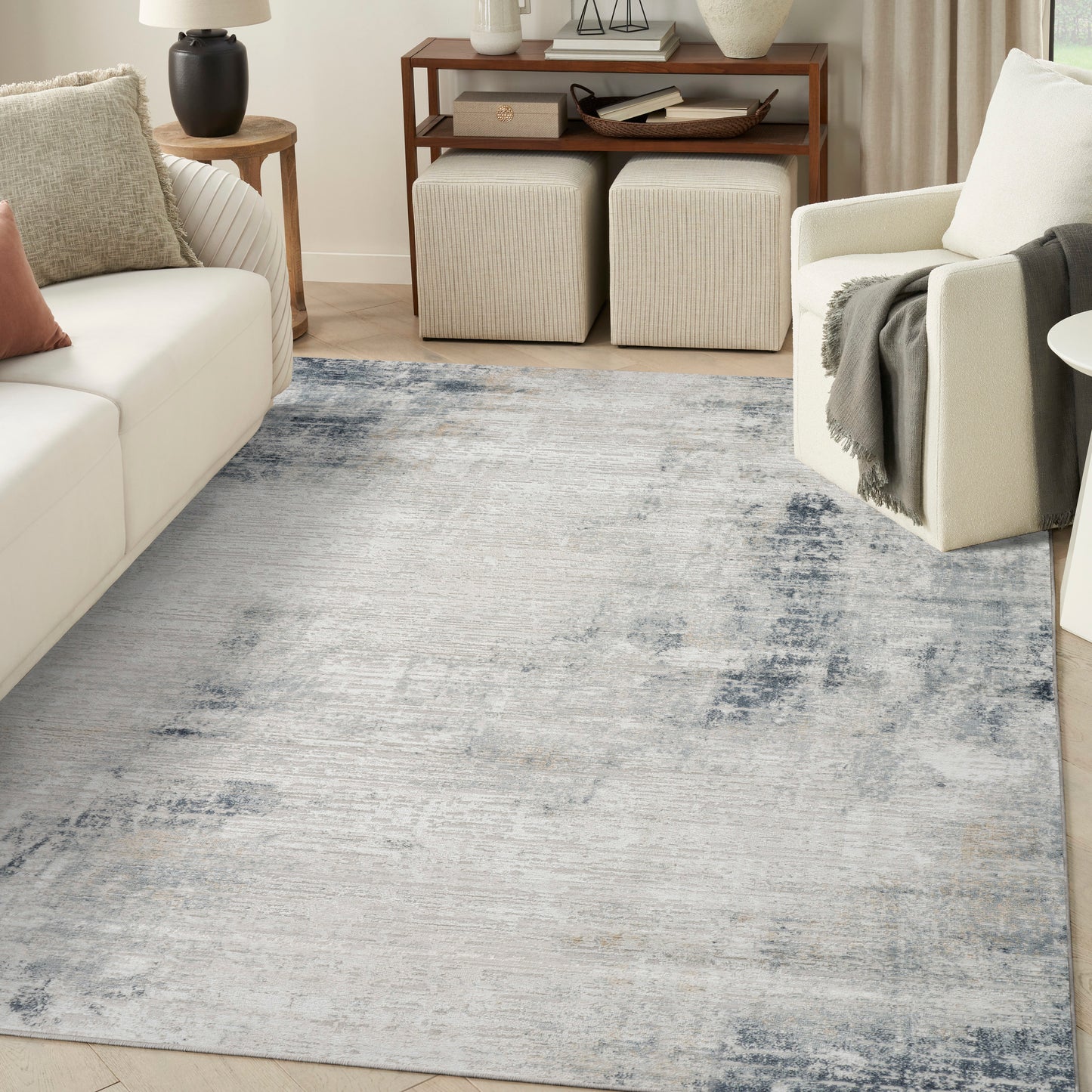 Rectangular blue-gray distressed area rug in a modern living room with cream sofa and armchair.