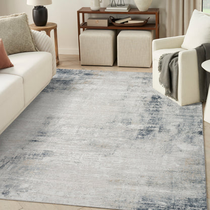 Rectangular blue-gray distressed area rug in a modern living room with cream sofa and armchair.