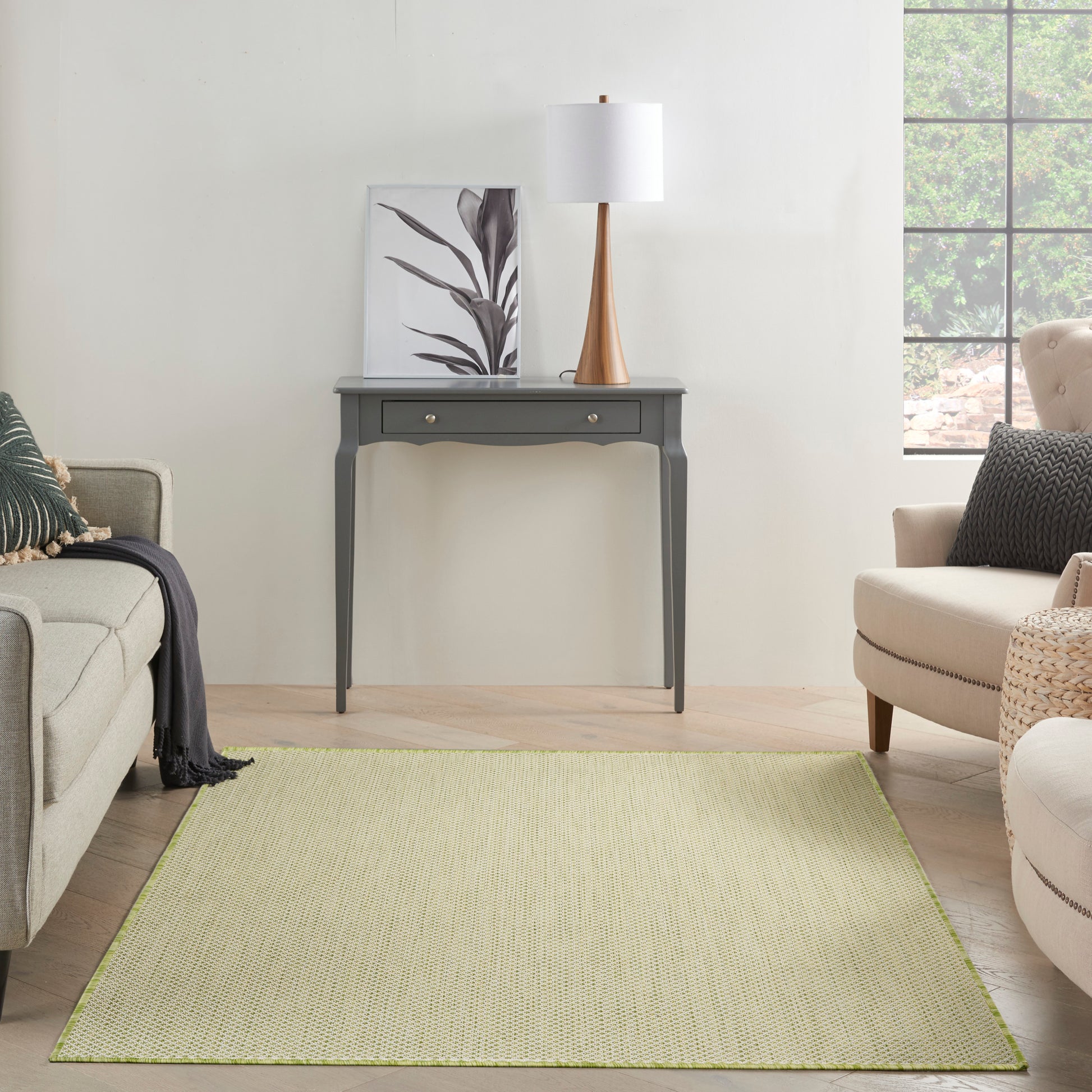 Rectangular lime-green woven rug in a modern living room with gray console table, white-shade lamp, & beige seating.
