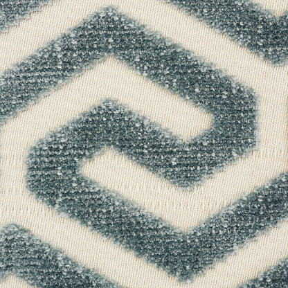 Close-up of a plush rug with blue-gray geometric diamond chevrons on cream background.