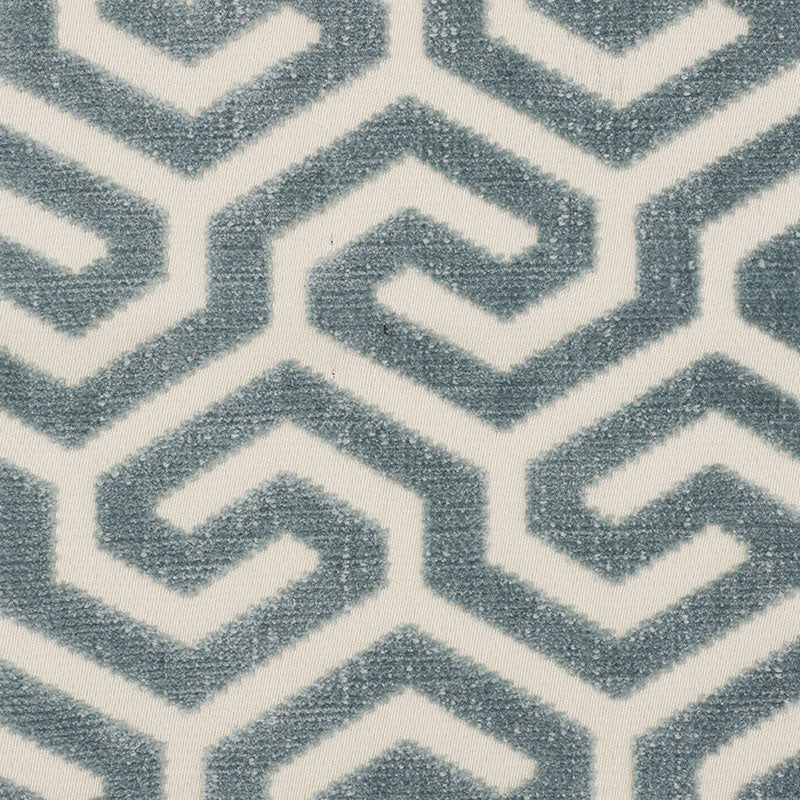 Blue-gray plush rug with interlocking geometric chevron pattern on white background.